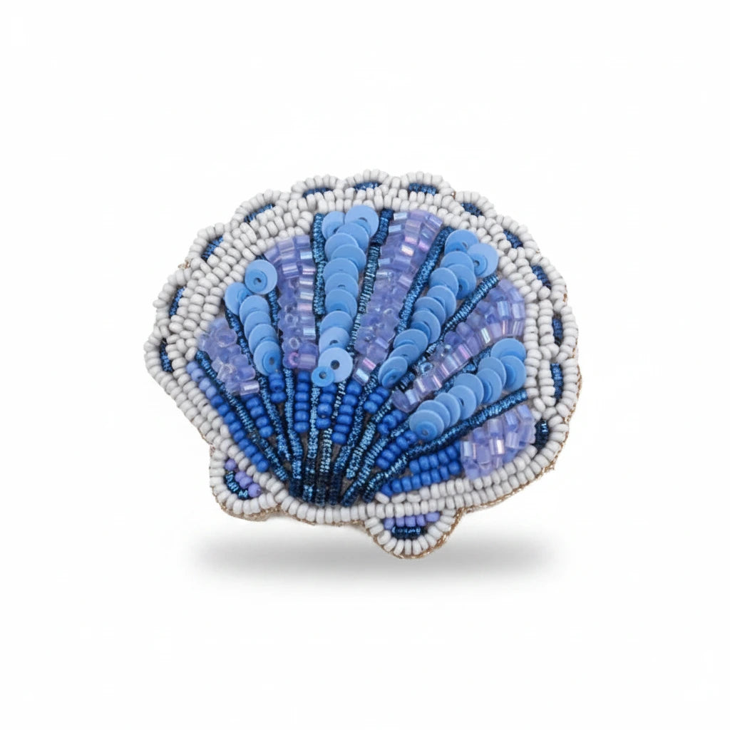 A scallop-shaped beaded brooch featuring shades of blue, purple, and white beads, isolated on a solid white background.