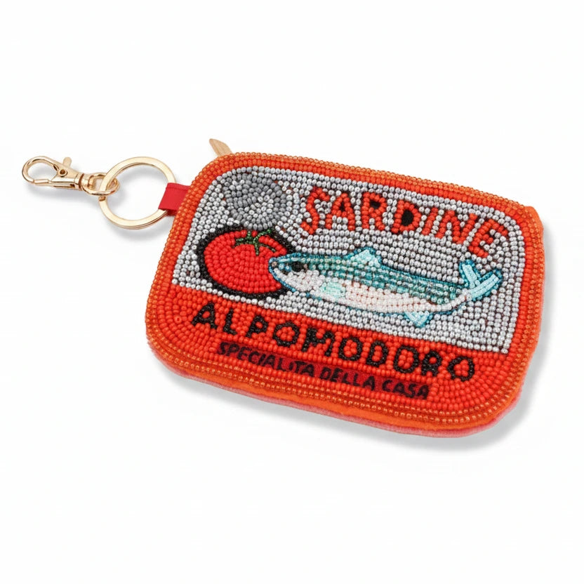 A small rectangular embroidered coin purse with a gold-tone keychain clasp. The purse features a vibrant orange border and a central graphic embellished with rhinestones, showing a sardine, a tomato, a blue sardine fish, and the text 'SARDINE ALPOMODORO' and 'SPECIALITA DELLA CASA'.