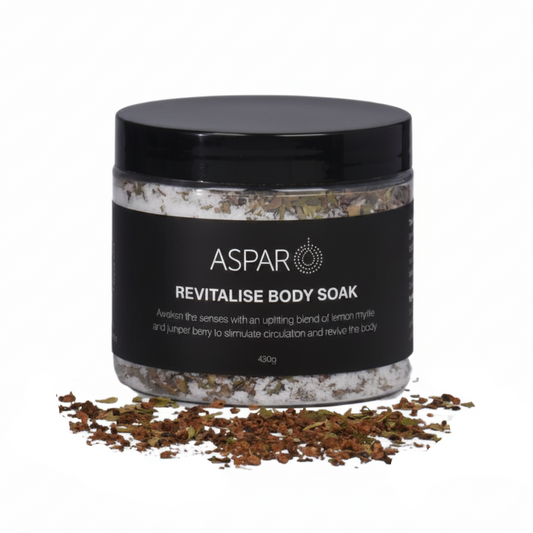 A jar of ASPAR Revitalise Body Soak with a black lid and black label, shown on a white background with loose bath salts scattered in front.